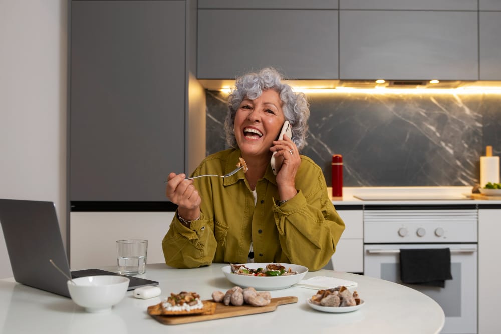 mature woman with food on the table trying to hear | Eat These 10 Foods to Keep Your Hearing Sharp as You Age—Audiologists Swear By Them