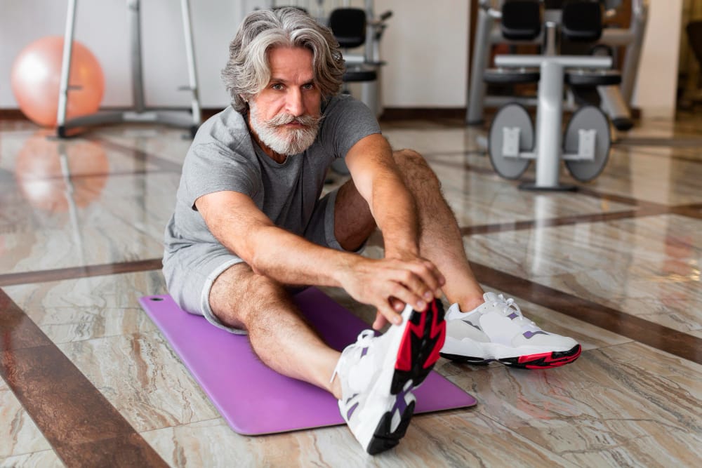 older man stretching on a yoga mat | Want to Stay Lean and Limber After 40? Do These 5 Exercises Every Day