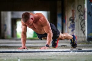 Shirtless caucasian man doing push-ups in an urban setting, showcasing strength and fitness. | Men Over 40: Fix Your Neck & Upper Back Pain with These 5 Uncommon Moves (From a Spine Surgeon!)