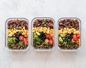 Colorful healthy meal prep with corn, olives, tomatoes, and lentils in glass containers. Perfect for mindful eating. | I Ate Lentils Every Day for a Month—Here’s What It Did to My Gut Health