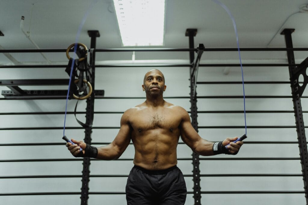 Fit man jumping rope shirtless in a gym setting, showcasing fitness and strength. | Get Shredded in 12 Weeks: The Ultimate Program to Stay Jacked Through 2025