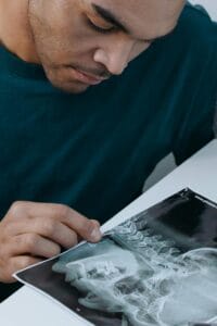 A dentist examining a dental x-ray closely for diagnostic purposes.