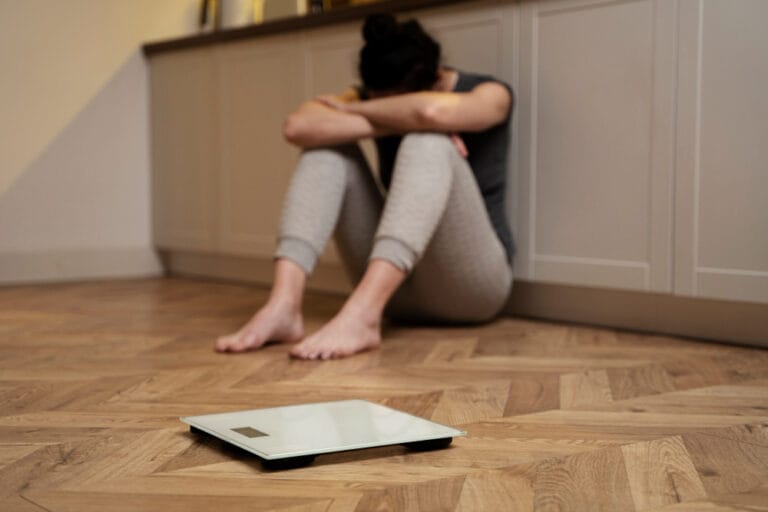 woman on a scale worried about her weight | Weight Loss Stuck? Dietitians Reveal 7 Hidden Reasons Your Calorie Deficit Isn't Working