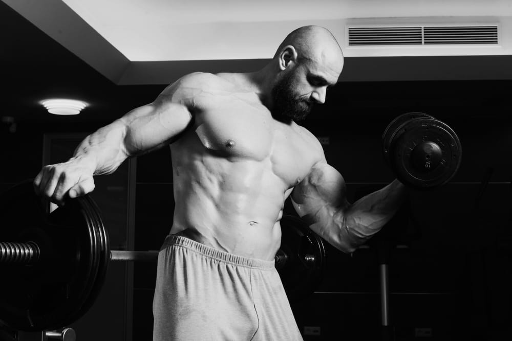 man lifting dumbbell | This Forgotten Bicep Trick From the Golden Era Builds Sleeve-Splitting Arms Fast