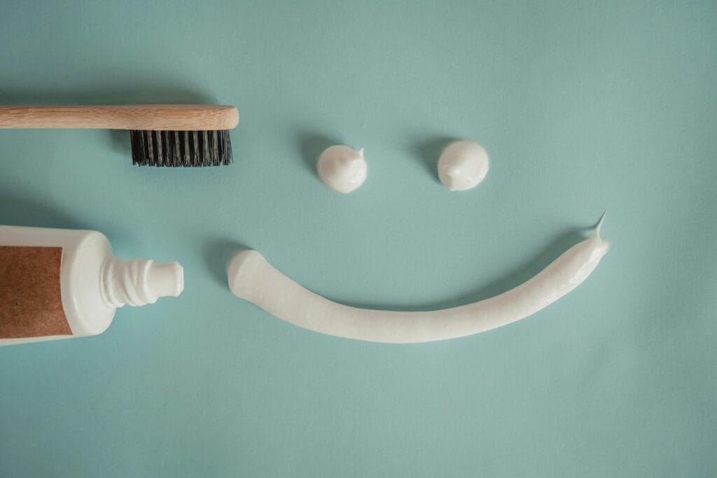 A playful arrangement of toothpaste and toothbrush forming a smile on a blue background.