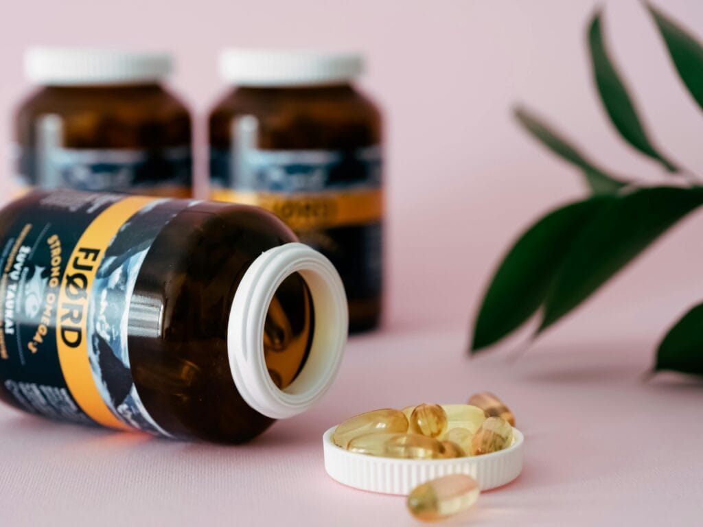 Close-up of omega-3 capsules and bottles on a pink background, ideal for health and wellness themes.