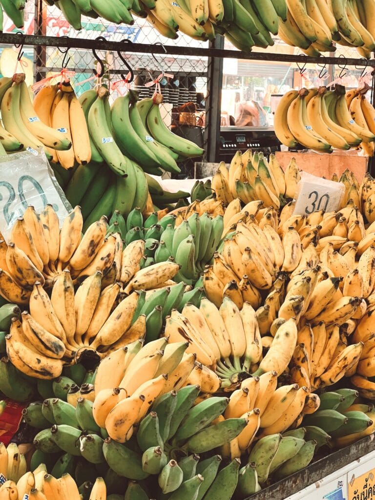 A vibrant display of ripe yellow and green bananas at an outdoor market.