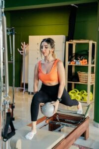 Fitness enthusiast performing reformer pilates exercises with equipment in a modern indoor studio.