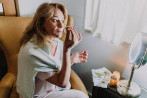 Woman indulging in self-care with a jade roller and candlelight ambiance indoors.