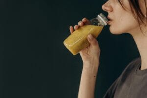 Side profile of a young woman sipping a nutritious smoothie from a bottle, showcasing a healthy lifestyle. | Feeling Tired or Tense? These 10 Magnesium-Packed Drinks Calm Your Mind and Build Muscle Fast
