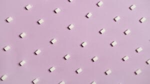 Geometric arrangement of white sugar cubes on a pastel pink surface.