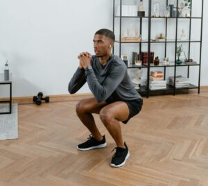 A man performs squats in a stylish indoor setting, embracing a healthy lifestyle.