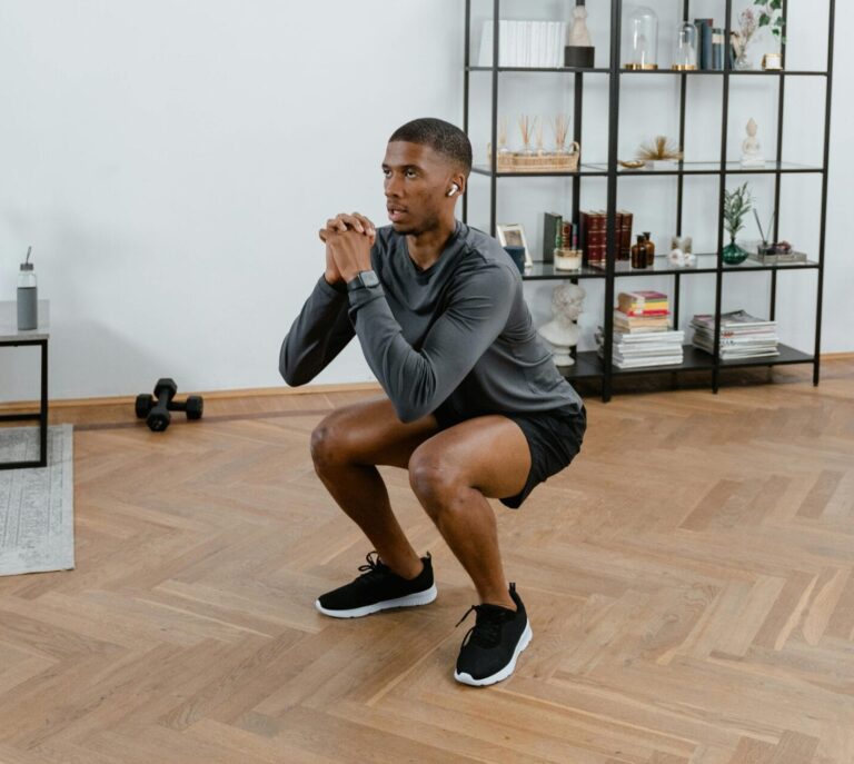 A man performs squats in a stylish indoor setting, embracing a healthy lifestyle.