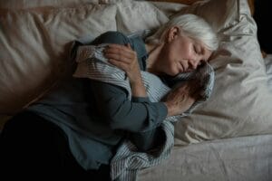 Senior woman sleeping peacefully in bed, conveying tranquility and rest.