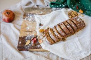 Freshly baked sliced bread on a wooden board, garnished with dried fruits.