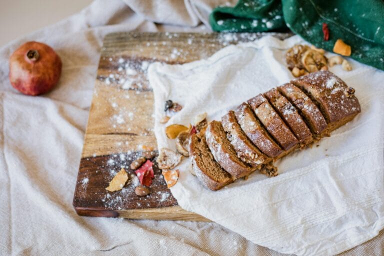Freshly baked sliced bread on a wooden board, garnished with dried fruits.