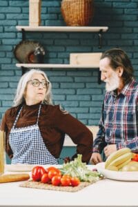 Elderly couple preparing food in the kitchen with fresh vegetables.