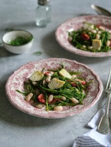 Delicious vegan salad with artichokes, beans, and greens, served on a decorative plate.