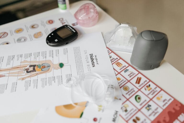 A comprehensive flat lay of diabetes management tools including a glucose meter and instructional flyers.