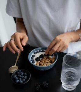 High-angle shot of a person preparing a berry and granola breakfast, emphasizing healthy eating.