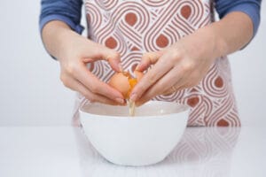 woman breaking an egg in a bowl