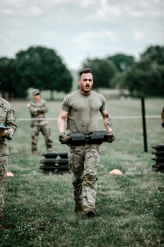 Soldiers engaged in rigorous outdoor training carrying weights in military gear.