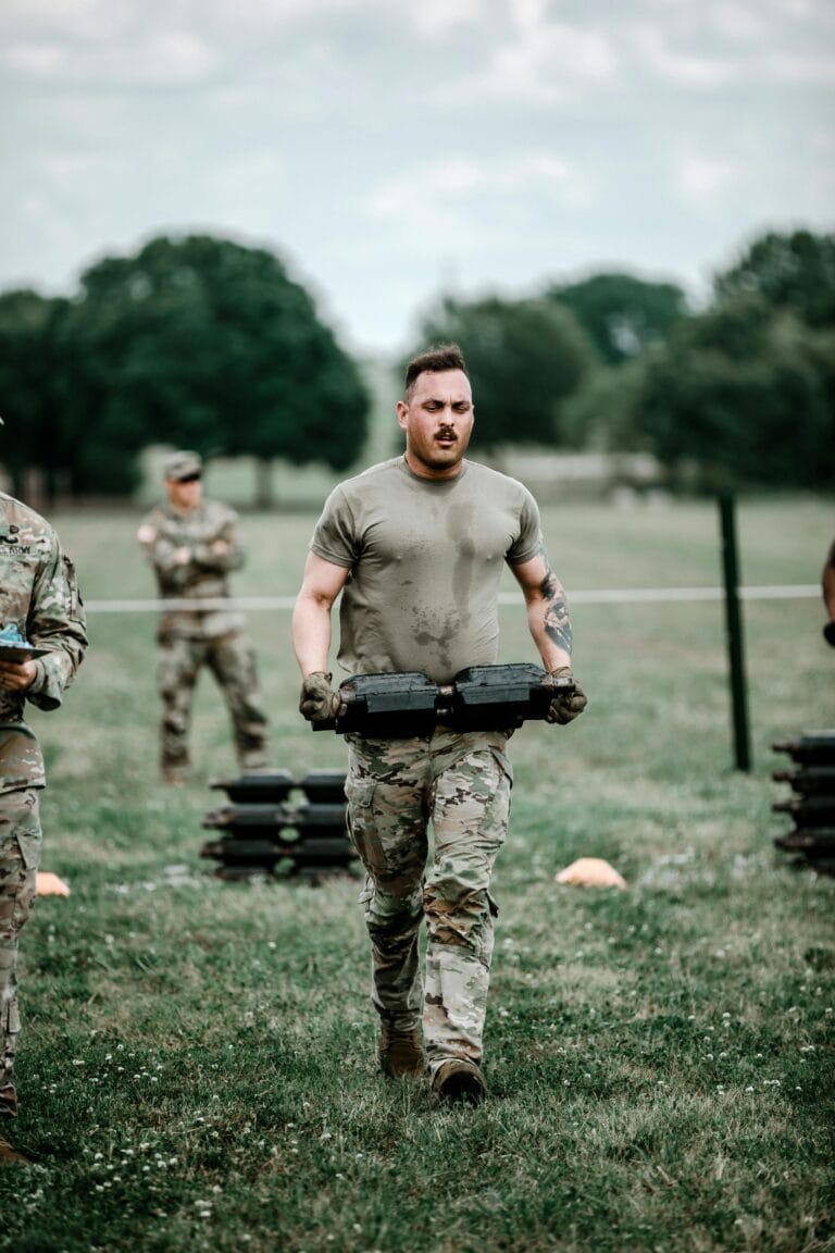 Soldiers engaged in rigorous outdoor training carrying weights in military gear.