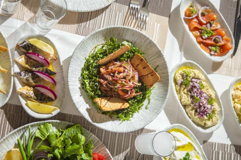 Top-down view of Mediterranean dishes including salads and seafood on an elegant table setting.