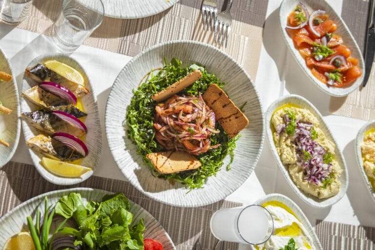 Top-down view of Mediterranean dishes including salads and seafood on an elegant table setting.