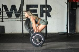 Athletic woman performing a deadlift exercise in a gym, showcasing strength and fitness.
