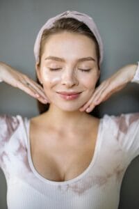 A serene portrait of a smiling woman with eyes closed, displaying elegance and tranquility. | face yoga