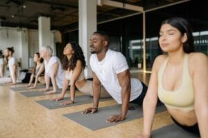 A diverse group of adults practicing yoga poses in a light-filled studio.