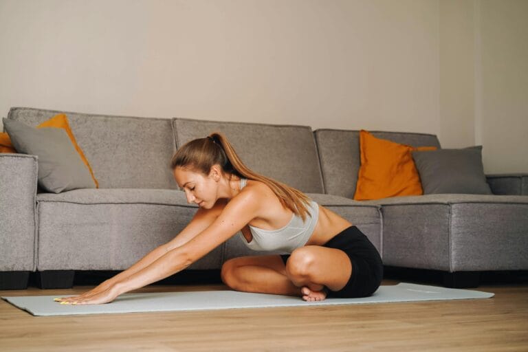 Woman practicing yoga indoors on a mat in a modern living room, embodying a healthy lifestyle.
