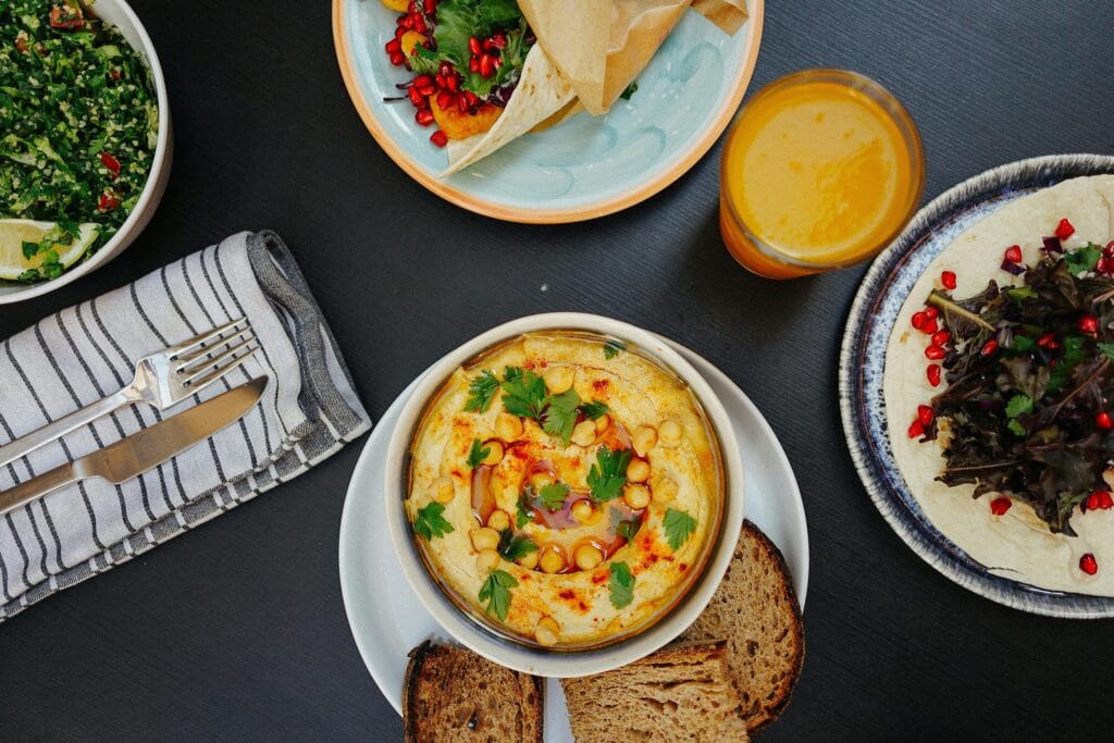 A vibrant Mediterranean meal featuring hummus, tabouli salad, bread, and fresh juice, perfect for healthy eating.