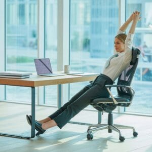 woman stretching in office next to her desk and workstation