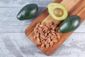 Top view of fresh avocados and almonds on a wooden board for a healthy snack.