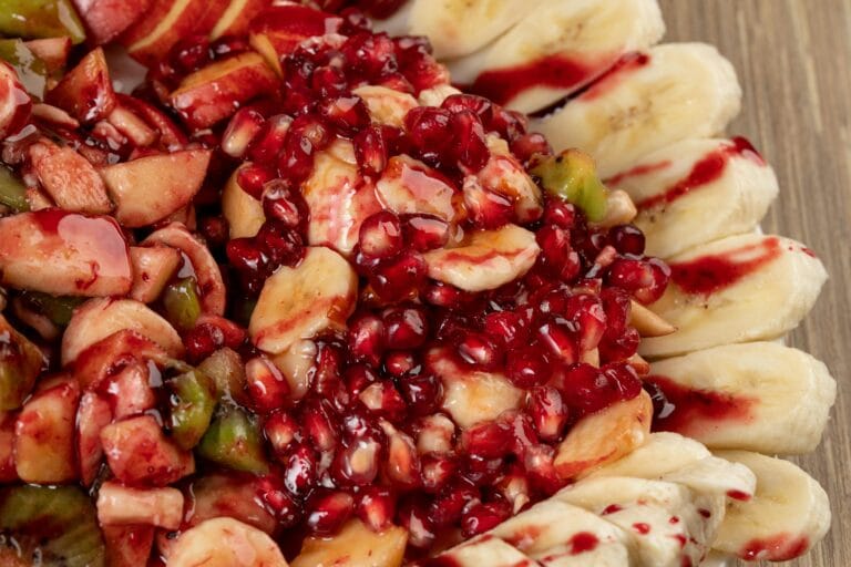 Colorful fruit salad with pomegranate, bananas, and apples. A fresh and healthy option.