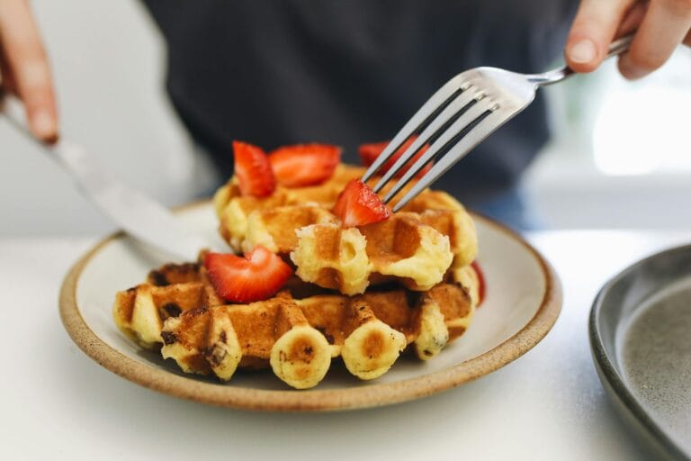Close-up of delicious waffles topped with fresh strawberries on a plate, perfect for brunch.