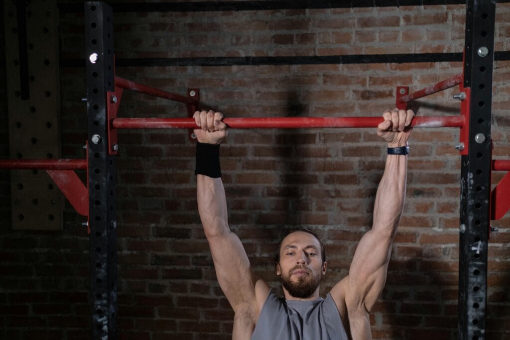 Man exercising on pull-up bar in gym, showcasing strength and fitness. dead hang