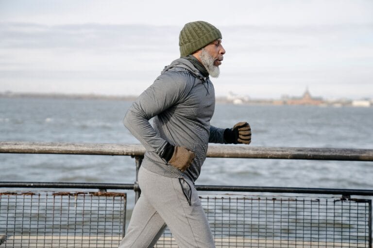 A senior man in activewear jogging along a waterfront, emphasizing fitness and healthy lifestyle.