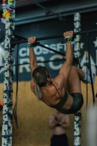 Athletic woman demonstrates strength with a pull-up in a gym environment, showing dedication and focus. | fit woman doing a pull up variation