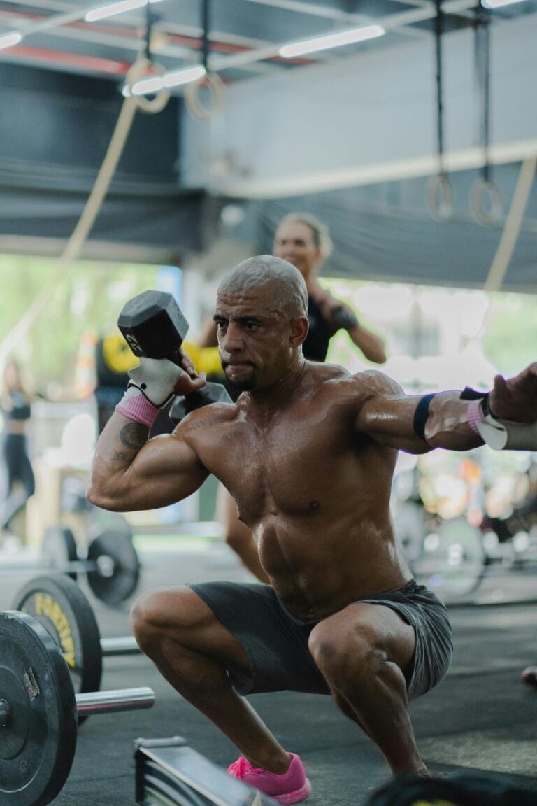 A muscular man performing a squat with a dumbbell in an indoor gym setting, showcasing strength and focus. | fit man