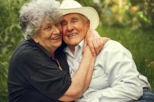 A joyful elderly couple hugging outdoors, exhibiting warmth and affection.