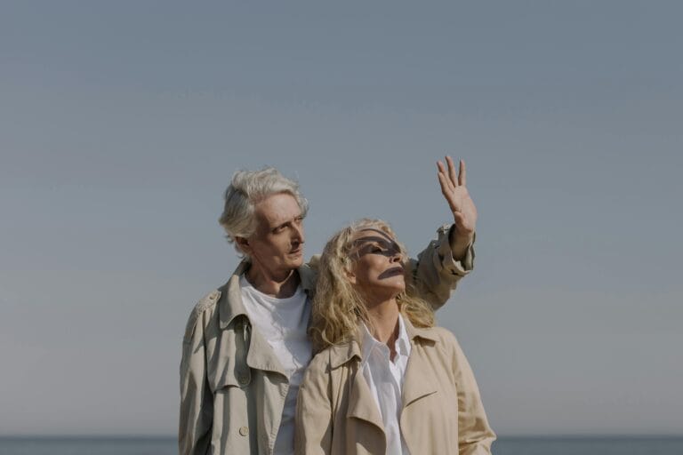 Stylish senior couple on a sunny beach enjoying a peaceful moment together.
