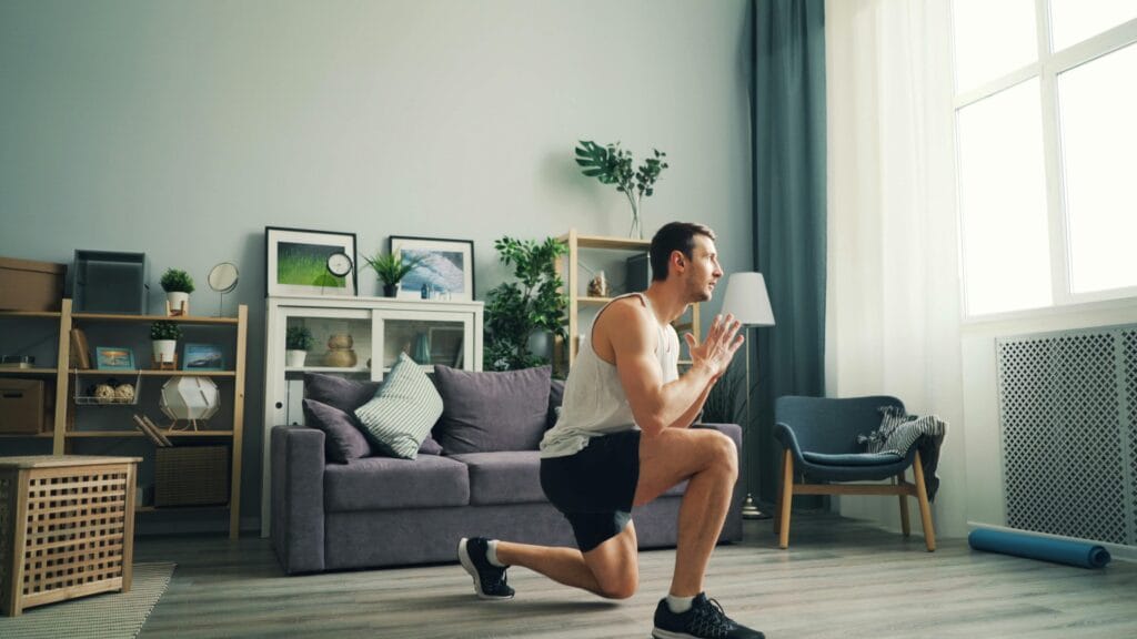 Adult male performing lunges indoors. Home fitness concept.