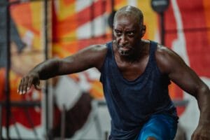 A strong, focused man engages in an intense indoor workout, showing determination and strength.