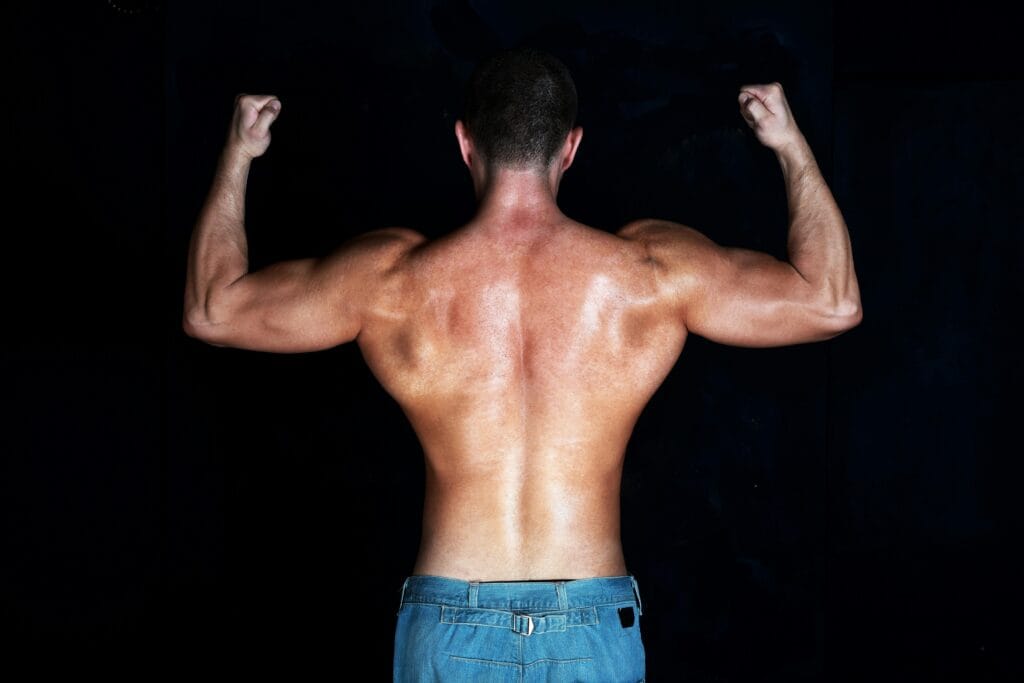 Shirtless athletic man showing defined back muscles in a strong pose.