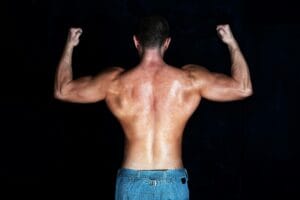 Shirtless athletic man showing defined back muscles in a strong pose.
