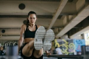 fit Woman exercising in gym wearing sports bra and shorts, focused and determined.