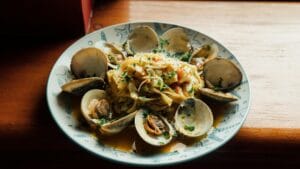 Plate of clams and pasta in a restaurant setting, showcasing a seafood meal.